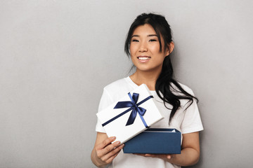 Asian beautiful young woman posing isolated over grey wall background near present gift box.