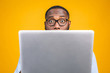 © denis_vermenko - Young surprised african american man standing and using laptop computer isolated over yellow background.