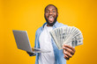 © denis_vermenko - Photo of a happy young afro american handsome man posing isolated over yellow wall background using laptop computer holding money.