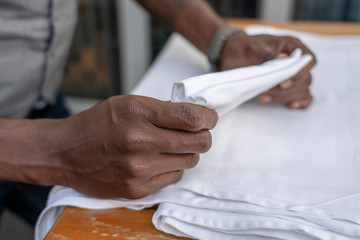 Wall Mural - Waiter folds napkins in restaurant. Waiters hands with white napkin closeup