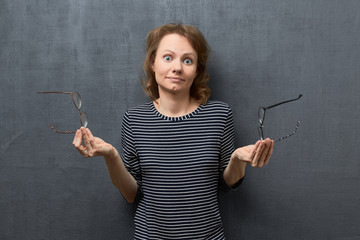 Portrait of puzzled girl trying to choose glasses