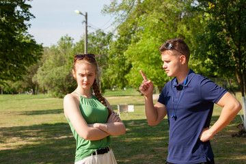 Young couple arguing while sitting on bench in park. Problems in relationship