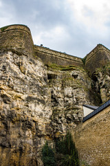 Wall Mural - Looking up at the Rock Walls of the Medieval Fortress Bock Casemates with the Cloudy Sky behind It in Luxembourg City, Luxembourg