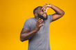 Afro american man isolated against yellow background smelling something stinky and disgusting, intolerable smell, holding breath with fingers on nose. Bad smells concept.