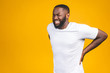 © denis_vermenko - Young afro american young man suffering from backache for having made an effort on isolated background.