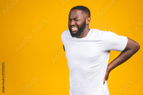 Cuadros en Lienzo Young afro american young man suffering from backache for having made an effort on isolated background