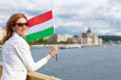 © sakkmesterke - Happy young woman holding Hungarian flag at Budapest