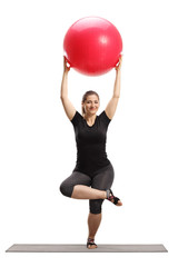 Sticker - Young woman lifting a fitness ball and exercising on a mat