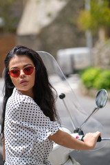 beautiful italian woman sitting on a italian scooter in Italy town