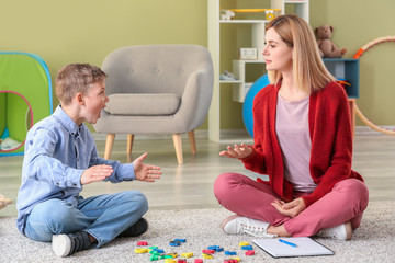 Wall Mural - Female psychologist working with boy suffering from autistic disorder