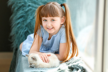 Wall Mural - Girl with cute fluffy kitten near window