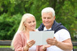 © Pixel-Shot - Portrait of happy mature couple reading book in park