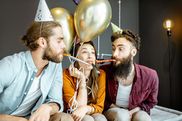 Wall Mural - Young friends having fun with whistles during the party or birthday celebration at home