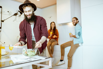 Wall Mural - Young friends talking and having some snacks during the meeting on the kitchen at home