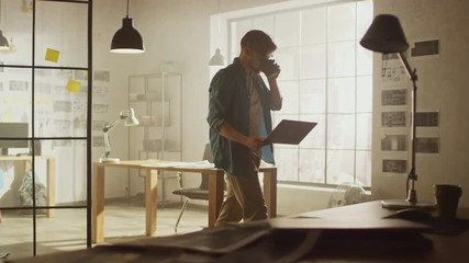Creative Developer Works on a Laptop in His Studio. Designing Apps, Games and Doing Video Editing. In the Background Modern Sunny Loft Office with Project Storyboard and Concepts Covering the Wall
