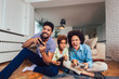 © Mediteraneo - Smiling family sitting on the couch together playing video games, selective focus.