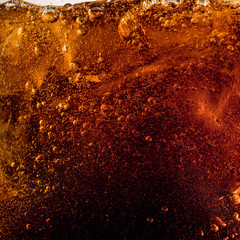 Close up view of the ice cubes in dark cola background. Texture of cooling sweet summer's drink with foam and macro bubbles on the glass wall. Fizzing or floating up to top of surface.