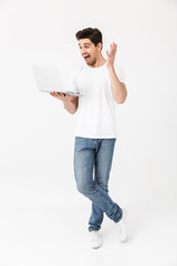 Poster - Shocked excited young man posing isolated over white wall using laptop computer.