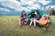 © Shutter2U - Two people talking near camping tent in meadow field. Male and female traveler looking at attraction view point. Couples adventure at outdoors together. People and lifestyles concept