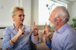 Smiling senior woman talking using sign language with her hearing impairment man
