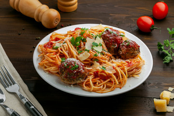 Wall Mural - Delicious spaghetti pasta with meatballs and tomato sauce on a plate. Traditional American Italian food on a rustic wooden table.