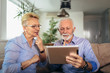 © Mediteraneo - Smiling deaf senior couple talking using sign language on the digital tablet's cam