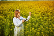 © bondvit - Agronomist woman or farmer examine blossoming rape (canola) field using tablet