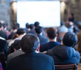 Seminar presenter at corporate conference giving speech. Speaker giving lecture to business audience. Defocused executive manager leading discussion in hall during company training event.