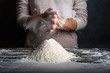 Female hands kneading dough for cooking bread, pizza or pasta. Cook clap hands with flour in the kitchen. Cloud of flour