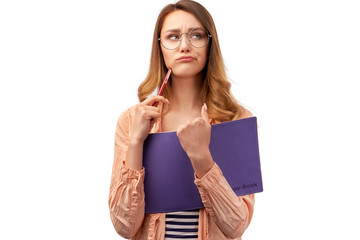 Disappointed female student frowns face, feels tired bored of cramming material, holds opened book, looks angrily aside, stands against white background with copy space for text and your advertising