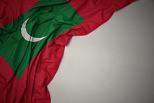Waving National Flag Of Maldives On A Gray Background.