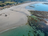 Fototapeta Na ścianę - Aerial view of wonderful beach with white sand and turquoise water, with some rocks  underwater and few people swimming. Aerial view South coast of Guernsey island, UK, Europe.