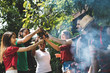 © tool51 - Group of people stand around cheering  drinking alcohol and eating at summer outdoor party and holidays concept.