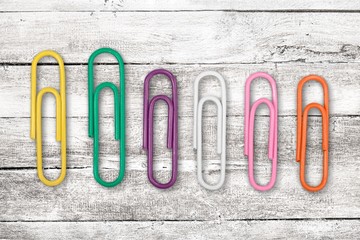 Colorful school supplies, color paper clip on wooden desk