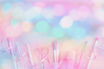 Wall Mural - Feminine nail polish accessories and unicorn makeup brushes on pink background with trendy festive pastel bokeh. Flat lay with copy space, beauty and cosmetics blogger concept