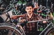 © Fxquadro - Pensive diligent man is fixing his own bike at busy bicycle warehouse.