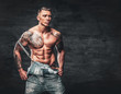 © Fxquadro - Studio portrait of handsome shirtless muscular, athletic male with a tattoo on his chest dressed in a jeans.