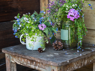 Bouquets of colorful field flowers. pine cones on an old stool on a rustic porch