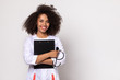 girl doctor with lush curly hair, in a medic uniform on a white wall. in the hands of girls stethoscope. The girl smiles and looks optimistic. free space for copy paste