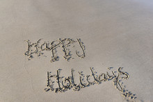 Happy Holidays Written On The Wet  Sand At Low Tide