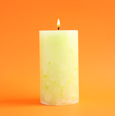 Alight scented wax candle on color background