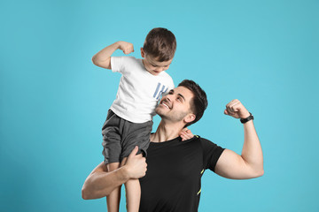 Wall Mural - Portrait of sporty dad and his son on color background