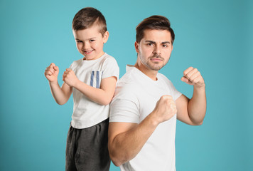 Canvas Print - Portrait of sporty dad and his son on color background