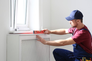 Canvas Print - Handyman in uniform working with building level indoors. Professional construction tools