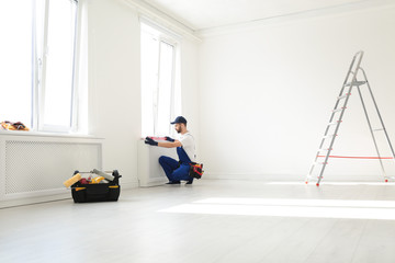 Wall Mural - Handyman in uniform working with building level indoors, space for text. Professional construction tools