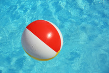 Colorful Beach Ball Floating In Swimming Pool On Sunny Day. Space For Text