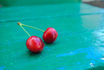 Wall Mural - Ripe juicy sweet cherry lies on a green wooden background.