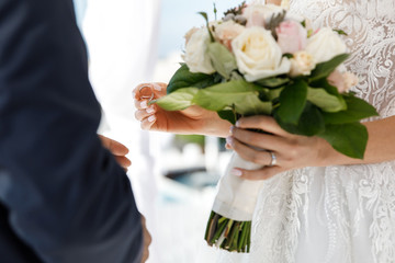 Marriage ceremony. The brides are exchanging wedding rings, the bride holds a wedding bouquet in her hand