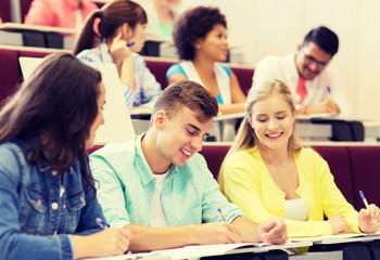 Poster - education, high school, university, learning and people concept - group of international students with notebooks writing in lecture hall