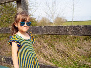 Adorable, smiling little girl in rustic dress and straw hat is playing in spring forest